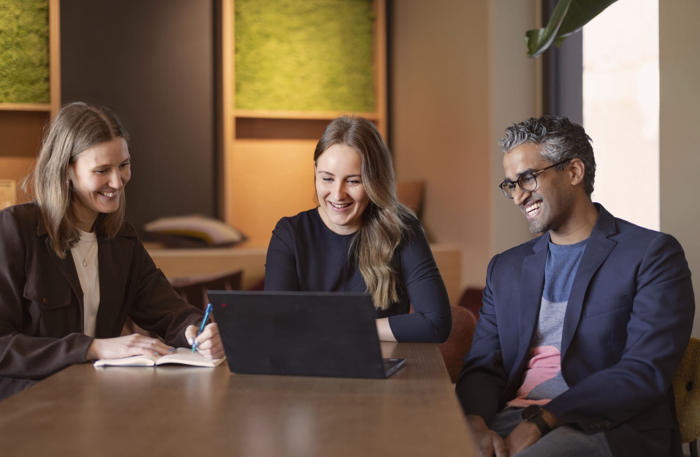 Three colleagues working together at a laptop.